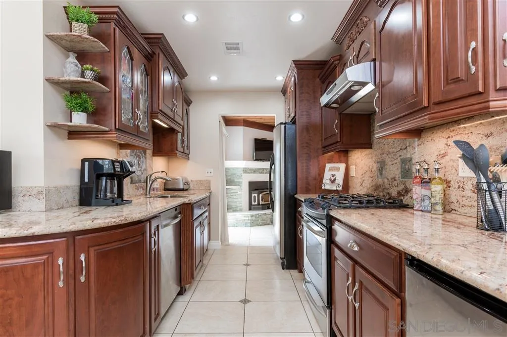 5168 Constitution Road San Diego, CA 92117 - Photo 8 of 25 a kitchen with stainless steel appliances granite countertop a sink a stove and a wooden cabinets