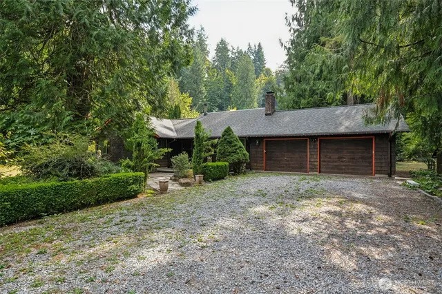 a view of a wooden house with a yard and large trees