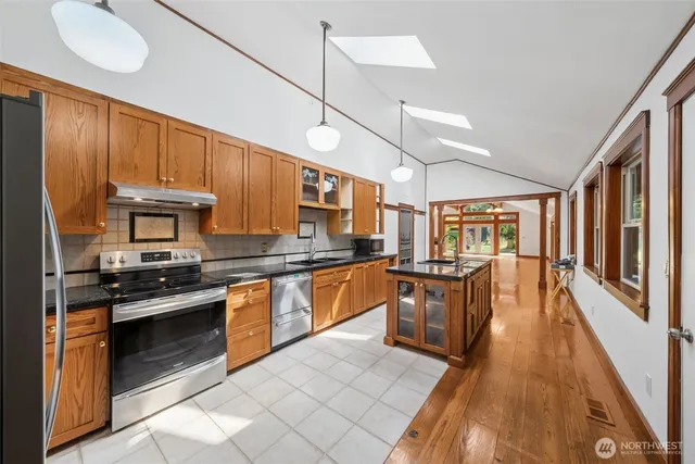 a kitchen with stainless steel appliances granite countertop wooden cabinets a stove top oven a sink and dishwasher