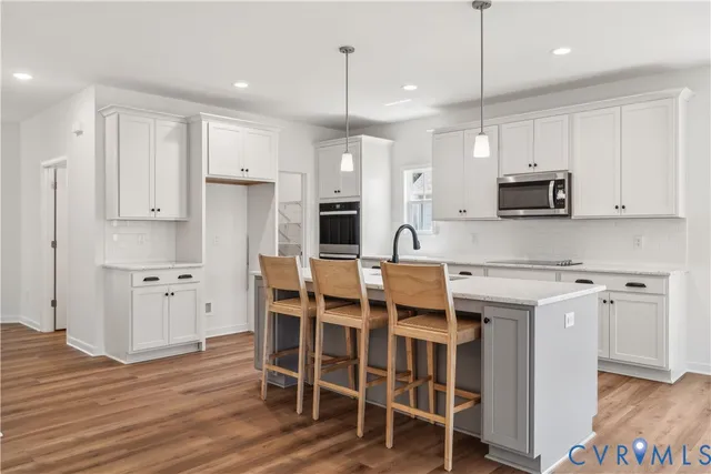 a kitchen with stainless steel appliances kitchen island granite countertop a table chairs microwave and sink