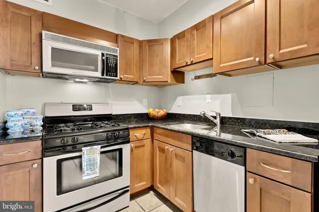 a kitchen with granite countertop cabinets stainless steel appliances and a wooden floor