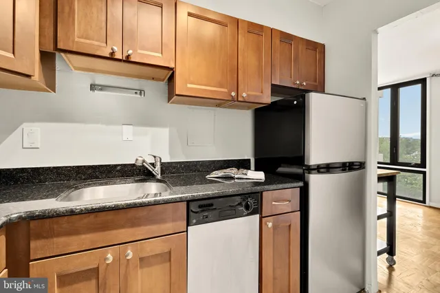 a kitchen with granite countertop a refrigerator sink and cabinets