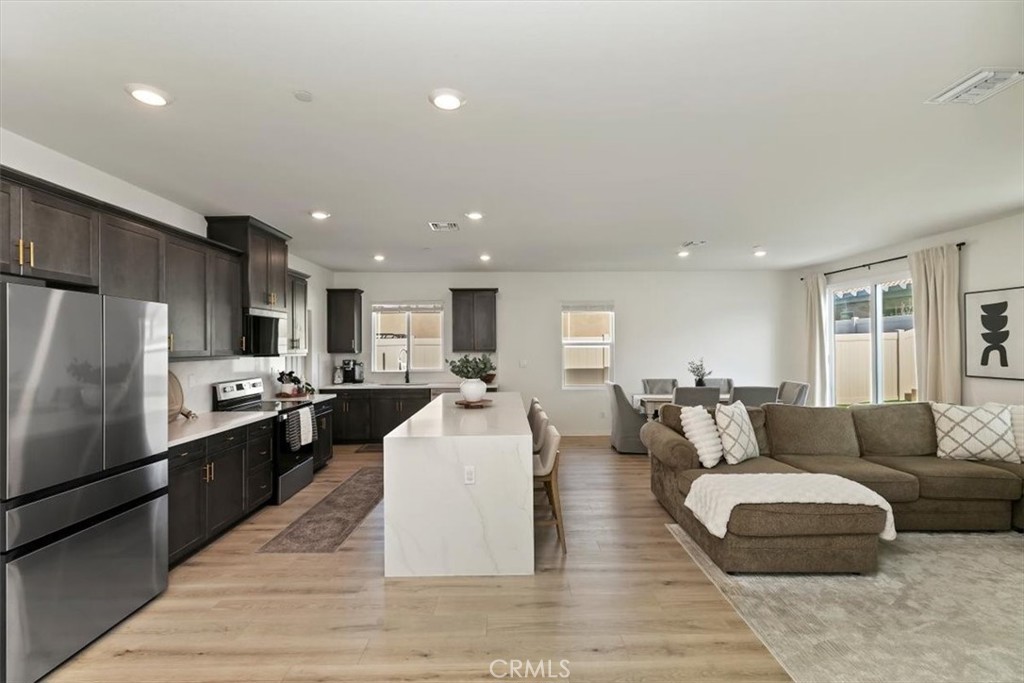 29224 Outback Lane Winchester, CA 92596 - Photo 14 of 35 a large living room with stainless steel appliances kitchen island granite countertop a couch and a view of kitchen