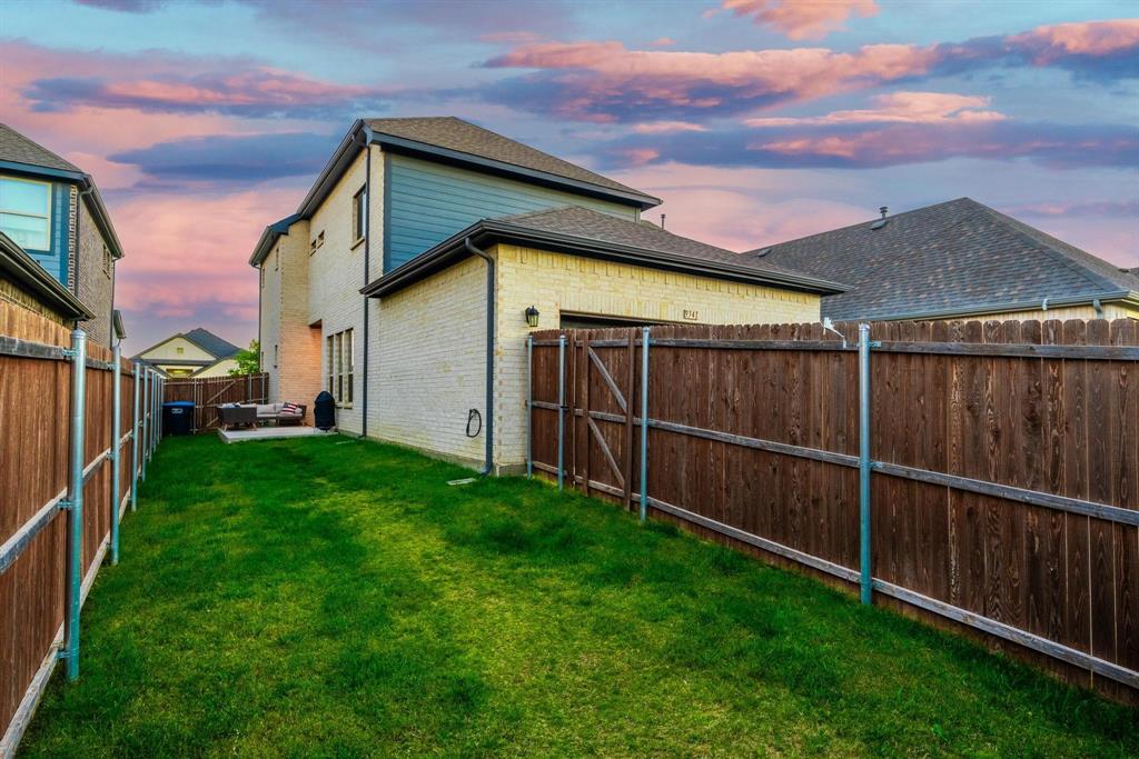 9341 Loggerhead Way Fort Worth, TX 76118 - Photo 30 of 35 Grassed backyard area featuring a concrete patio, brick exterior, dark siding accents, and a privacy fence with gate