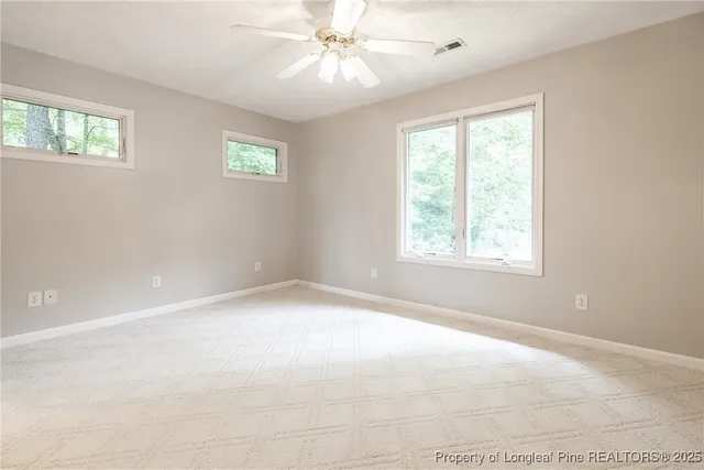 an empty room with windows and fan