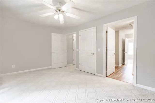 a view of a room with a ceiling fan and carpet
