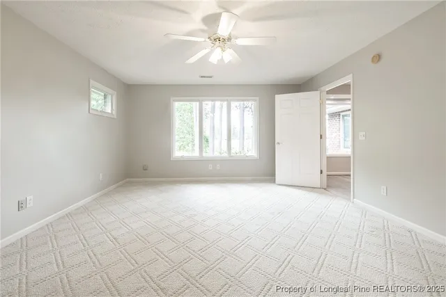 an empty room with windows and chandelier fan