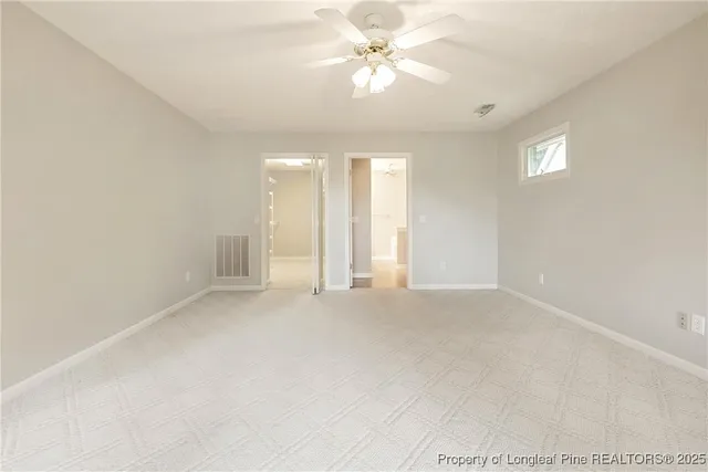 an empty room with chandelier fan and windows