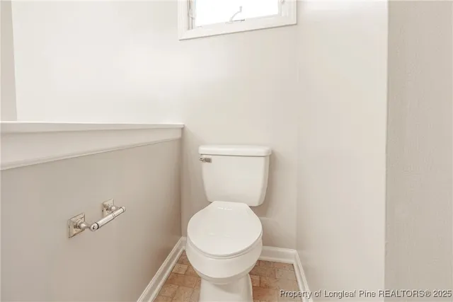 a white toilet sitting next to a white wall