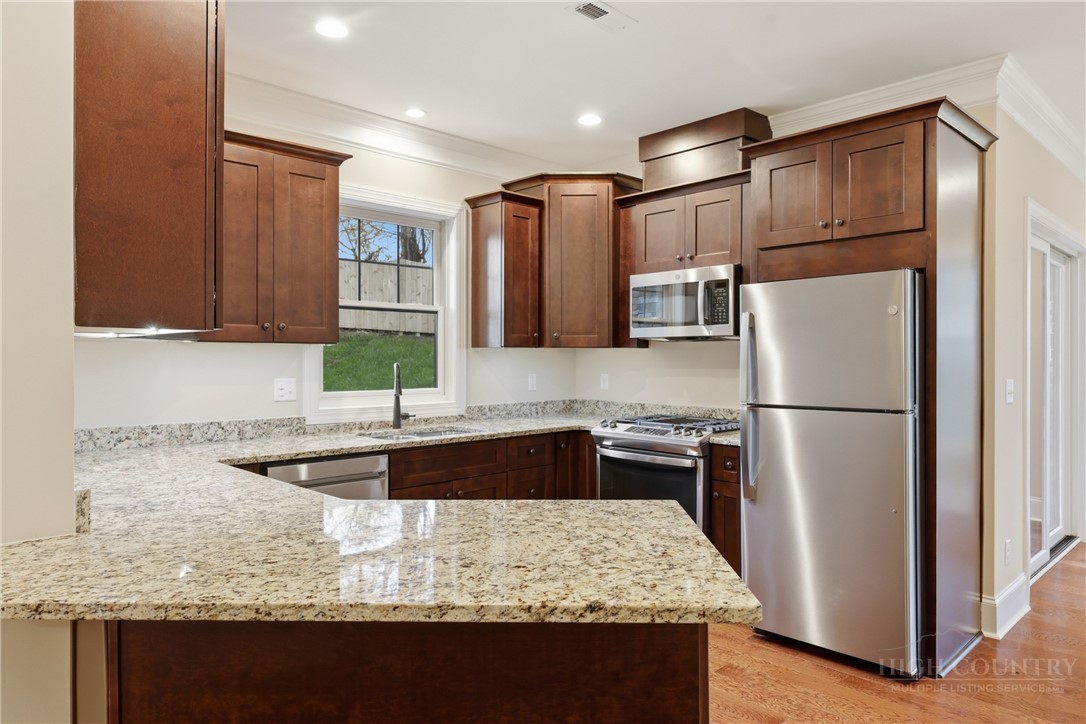 155 Gateway Drive, Unit 101 Boone, NC 28607 - Photo 7 of 50 a kitchen with granite countertop kitchen island stainless steel appliances a refrigerator a sink and wooden cabinets