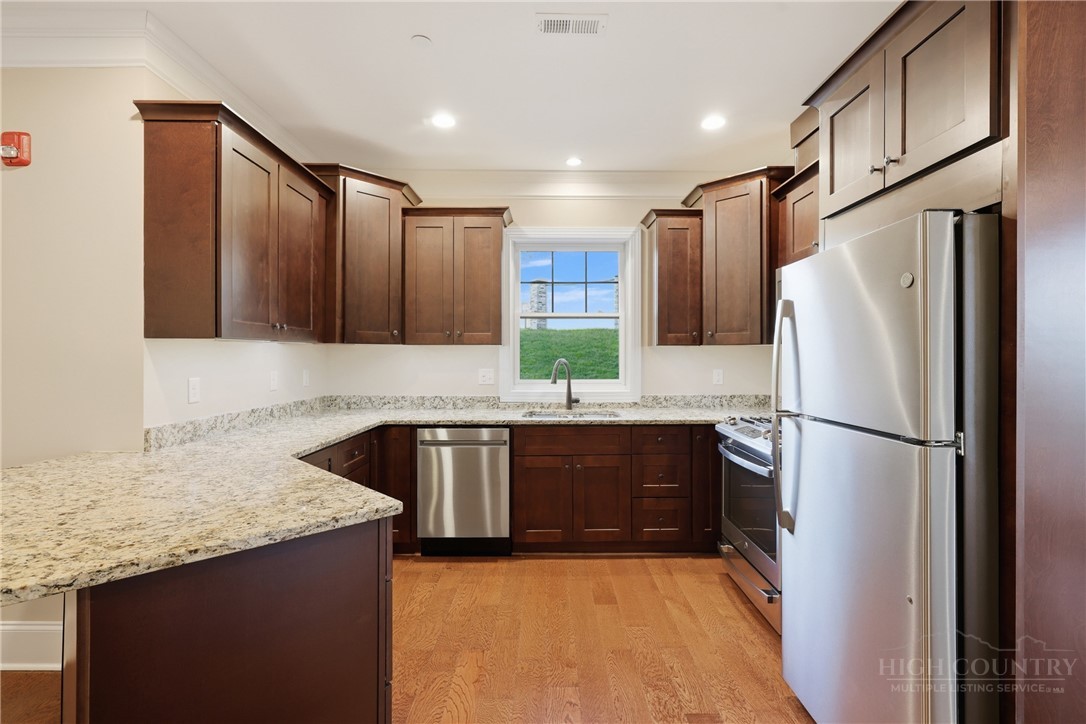 155 Gateway Drive, Unit 101 Boone, NC 28607 - Photo 8 of 50 a kitchen with granite countertop a refrigerator a sink and wooden cabinets