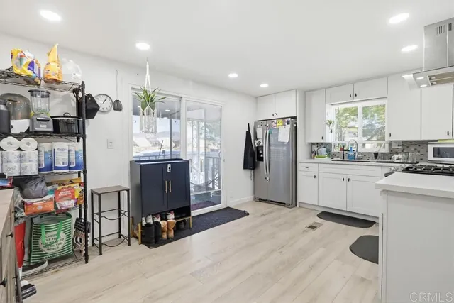 a kitchen with stainless steel appliances kitchen island granite countertop a refrigerator a stove a sink dishwasher and white cabinets with wooden floor