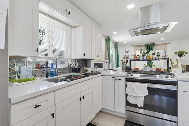 a kitchen with kitchen island granite countertop stainless steel appliances a sink a stove and cabinets