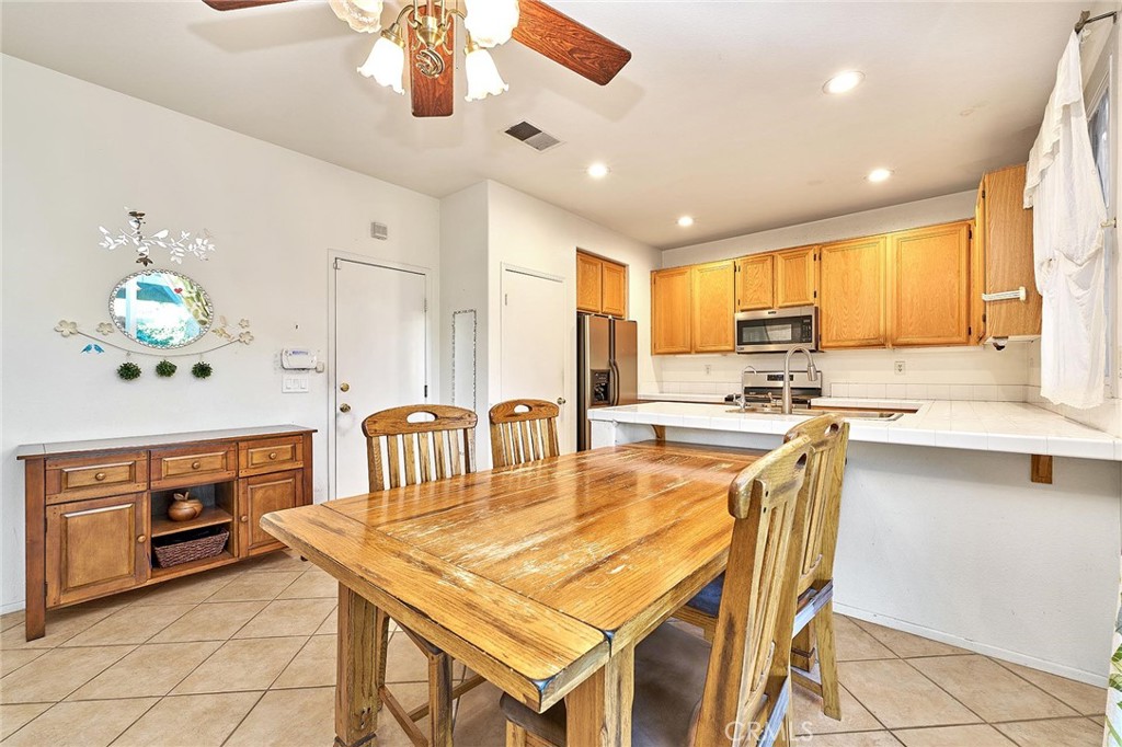 7371 Correspondence Place Rancho Cucamonga, CA 91730 - Photo 15 of 39 a kitchen with stainless steel appliances kitchen island granite countertop a stove a sink a refrigerator with a dining table and chairs