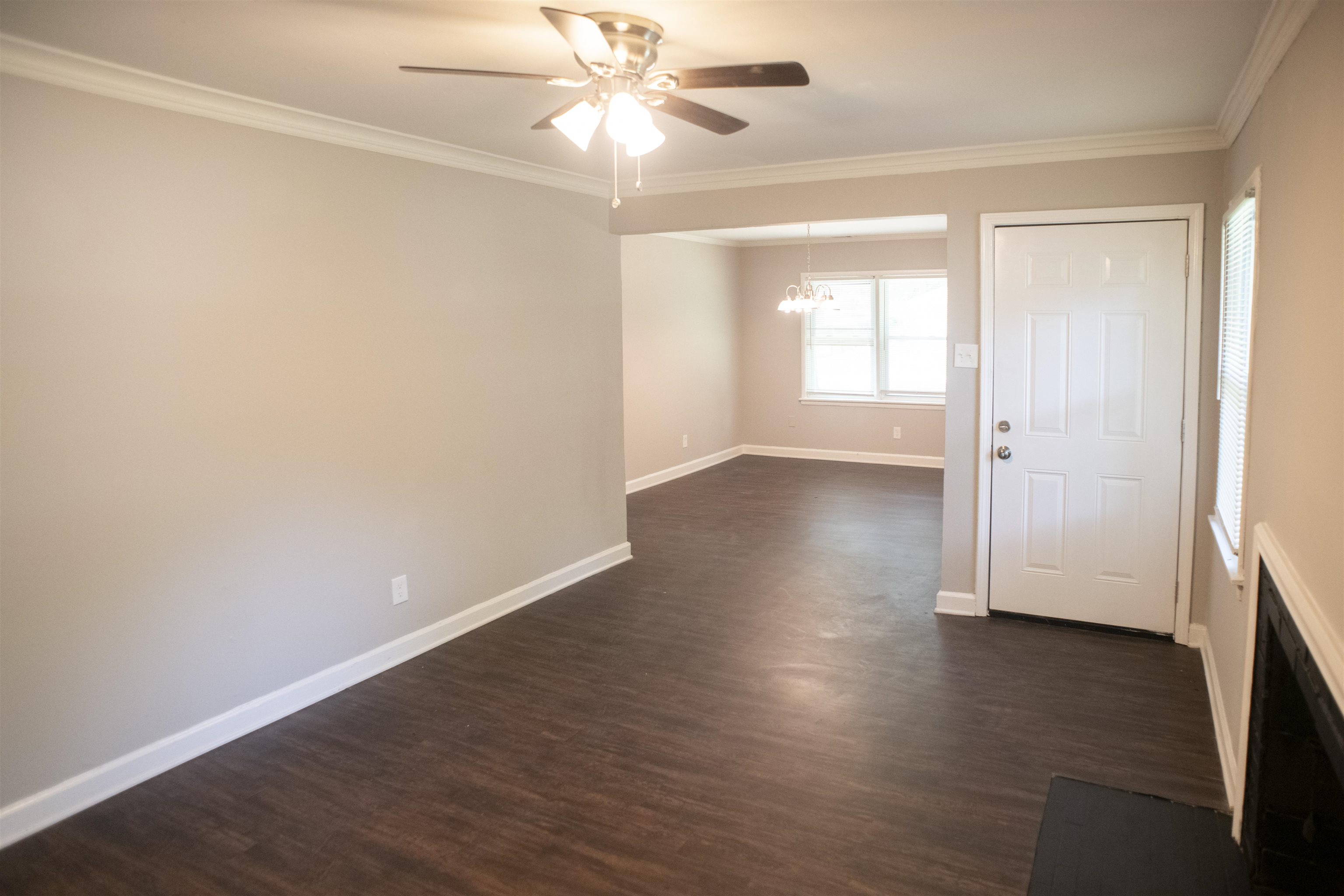 875 Enfield Road Memphis, TN 38116 - Photo 11 of 14 Spacious open-concept living area featuring dark wood-finish flooring throughout, neutral wall finishes, and abundant natural light from multiple windows