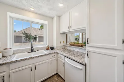 a kitchen with granite countertop white cabinets and a sink