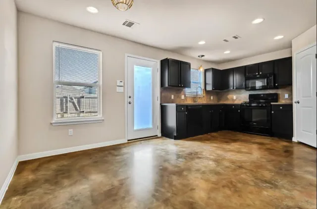 a view of kitchen with stainless steel appliances granite countertop a refrigerator and a stove top oven