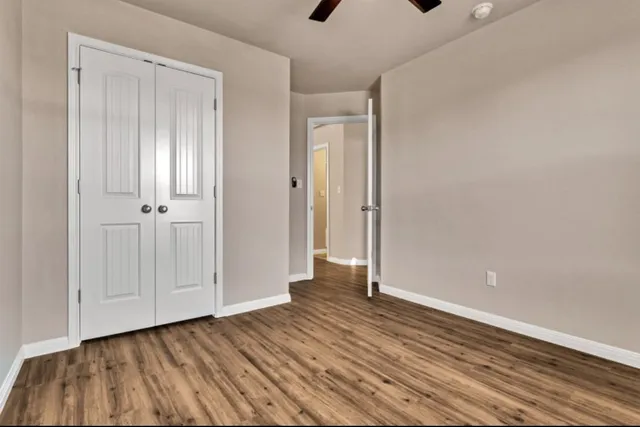 a view of an empty room with closet and wooden floor