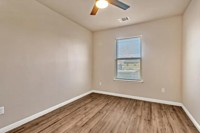 an empty room with a window and wooden floor