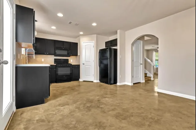 a view of kitchen with stainless steel appliances kitchen island empty cabinets and wooden floor