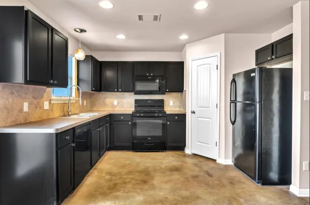 a kitchen with stainless steel appliances granite countertop a refrigerator and a stove top oven