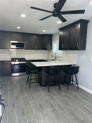 a kitchen with stainless steel appliances kitchen island granite countertop a sink cabinets and wooden floor