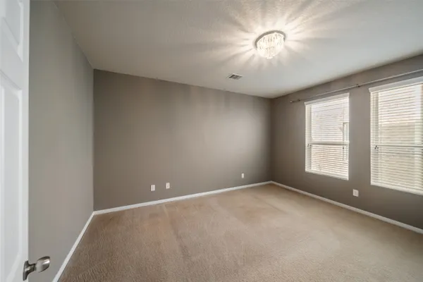 an empty room with windows and chandelier fan
