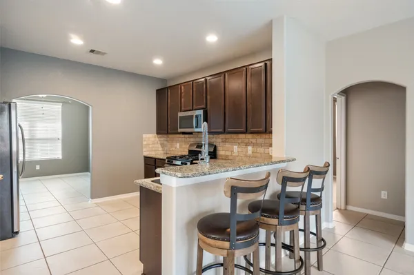a kitchen with granite countertop a stove a sink a dining table and chairs