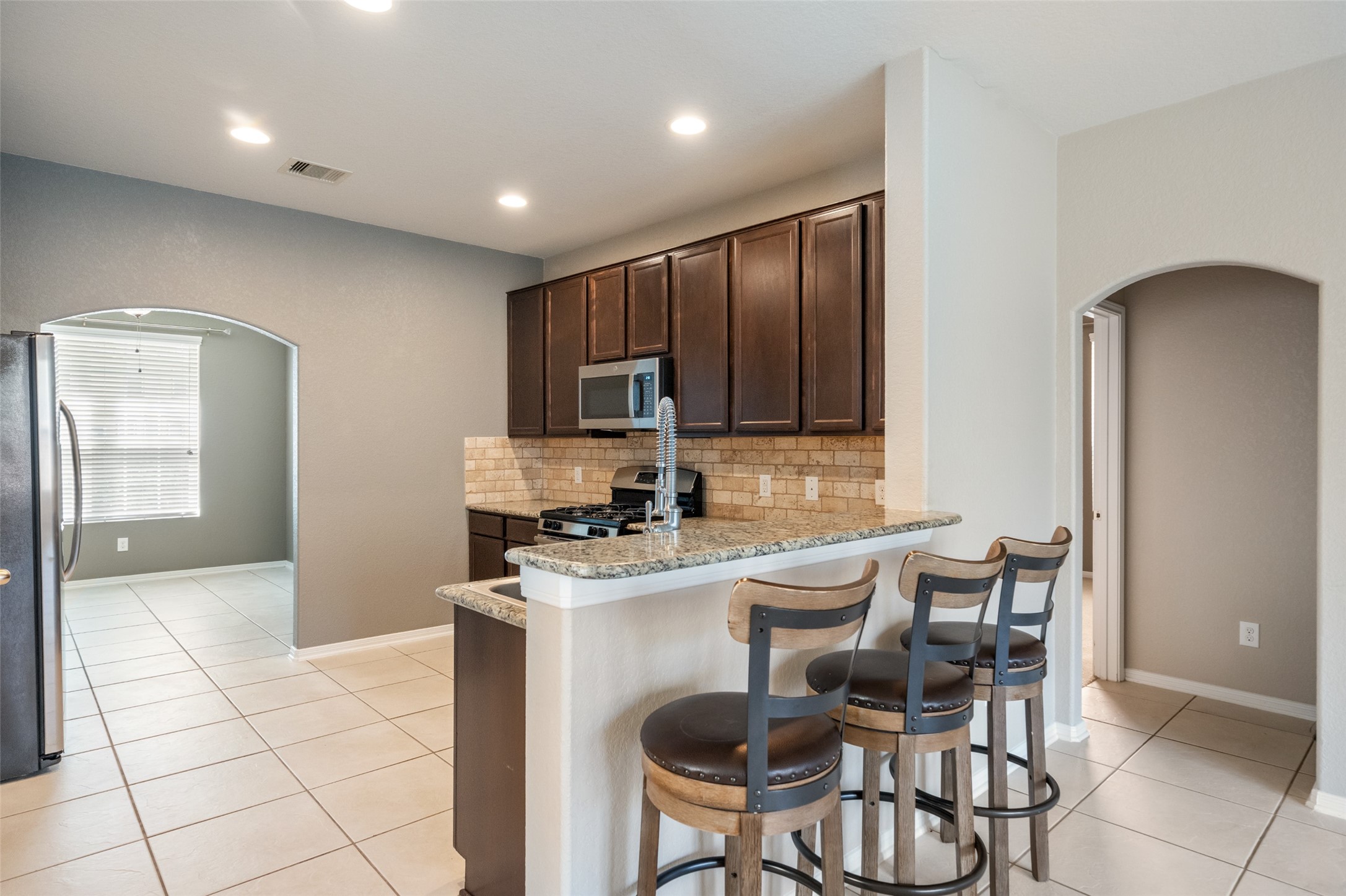 28915 Birch Green Way Spring, TX 77386 - Photo 8 of 30 a kitchen with granite countertop a stove a sink a dining table and chairs