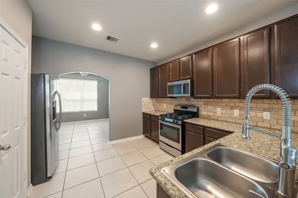 a kitchen with granite countertop a sink a stove and cabinets