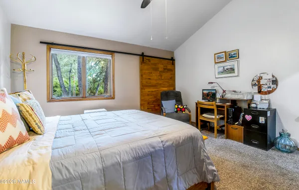 a bedroom with a bed a large window and a large mirror on the dresser
