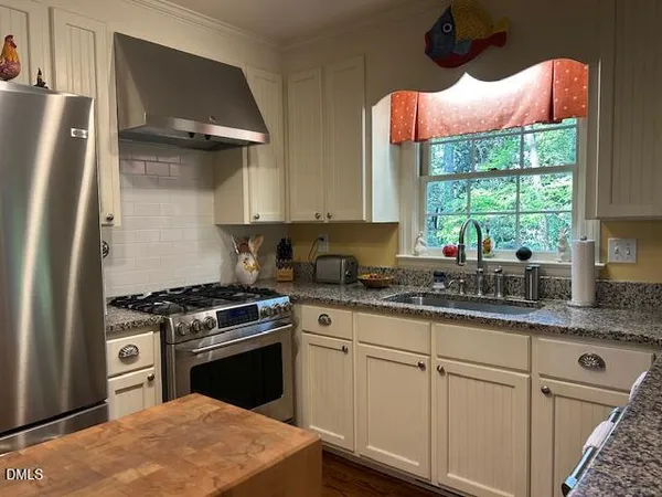 a kitchen with stainless steel appliances granite countertop a stove a sink and a refrigerator