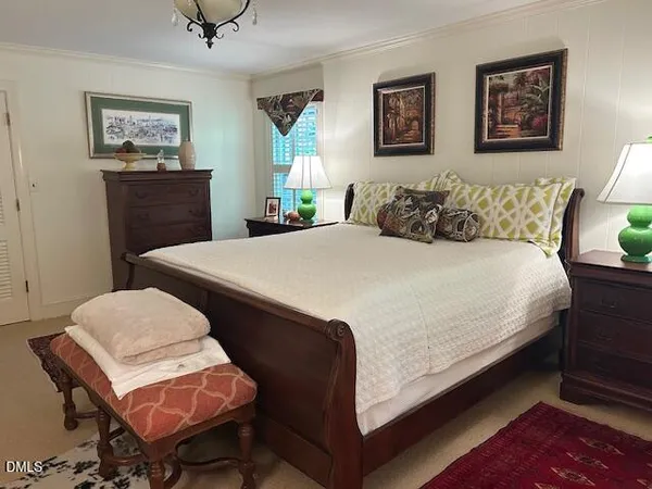 a bedroom with a bed a chair and painting on the wall