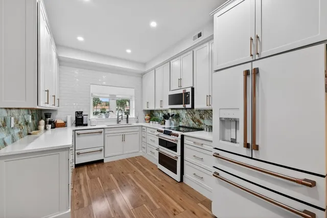 a kitchen with white cabinets and stainless steel appliances