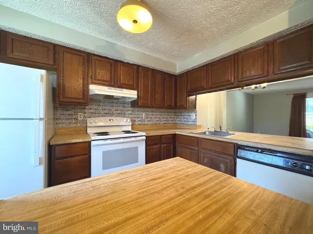 a kitchen with granite countertop wooden cabinets and stainless steel appliances