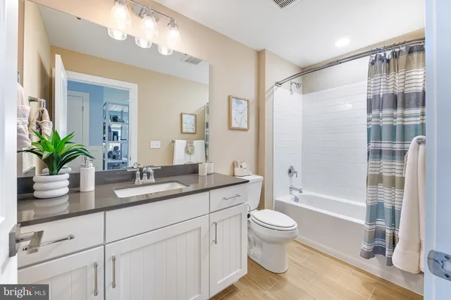 a bathroom with a granite countertop sink a toilet a large mirror and shower