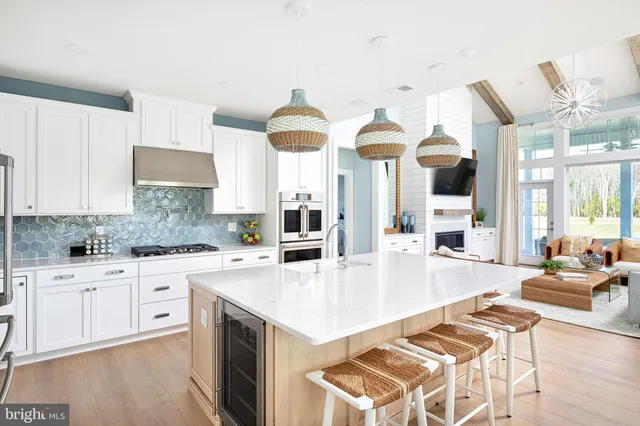 a large kitchen with stainless steel appliances granite countertop a stove a sink dishwasher and white cabinets with wooden floor