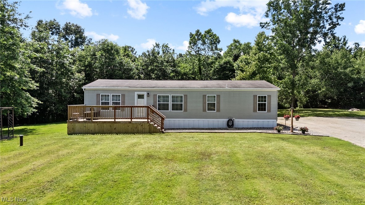 Manufactured / mobile home with a wooden deck and a front yard