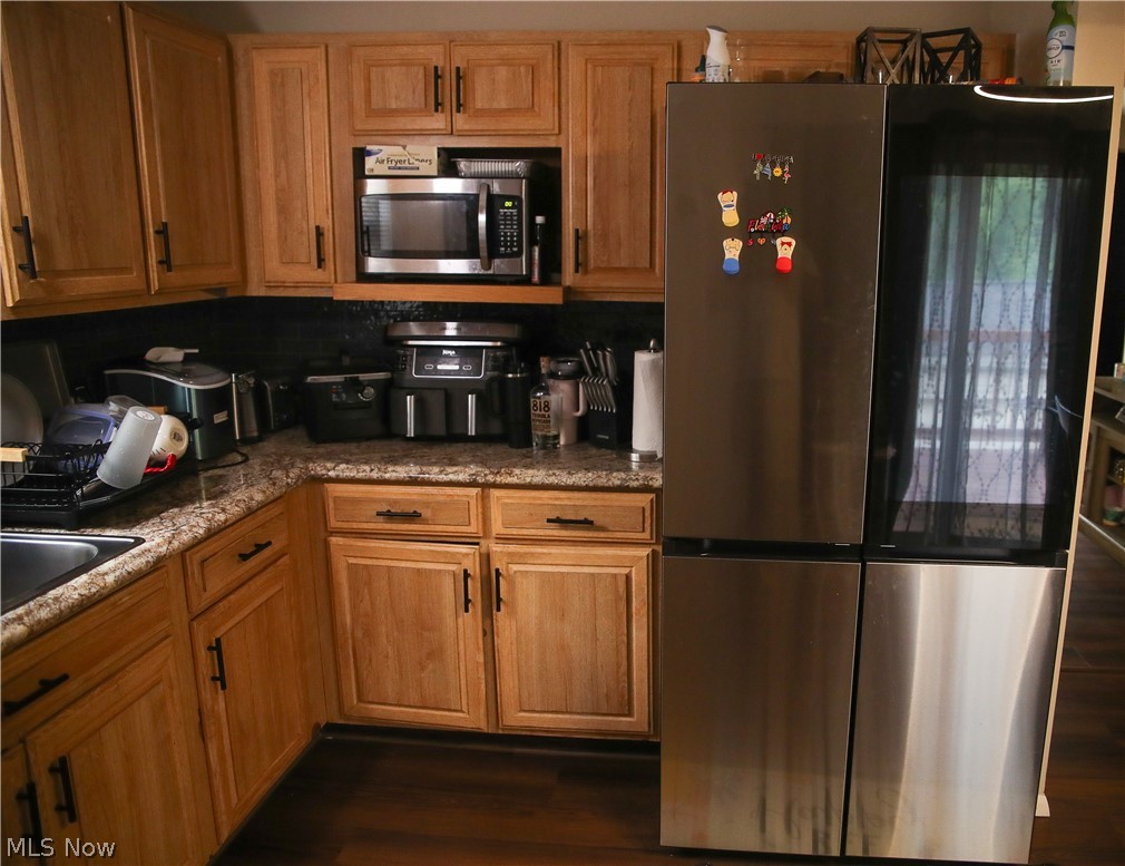 1258 Vane Avenue Akron, OH 44310 - Photo 6 of 12 Kitchen featuring wood cabinetry with dark hardware, granite-look countertops, and a dark tile backsplash