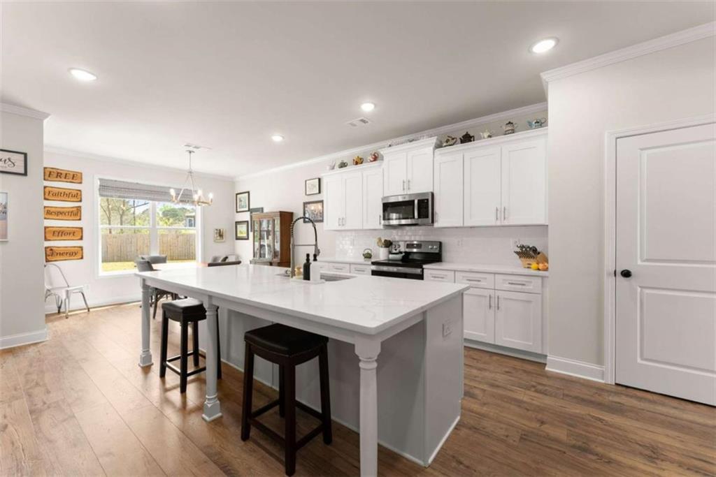 568 Dunagan Court Winder, GA 30680 - Photo 20 of 61 a kitchen with stainless steel appliances a white stove top oven a sink dishwasher and a refrigerator with wooden floor