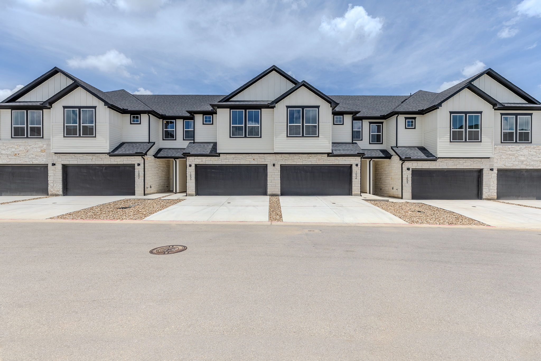 2600 Gattis School Road, Unit 1002 Round Rock, TX 78664 - Photo 1 of 40 Modern townhomes feature bold, dark trim against light siding, offering a stylish curb appeal.