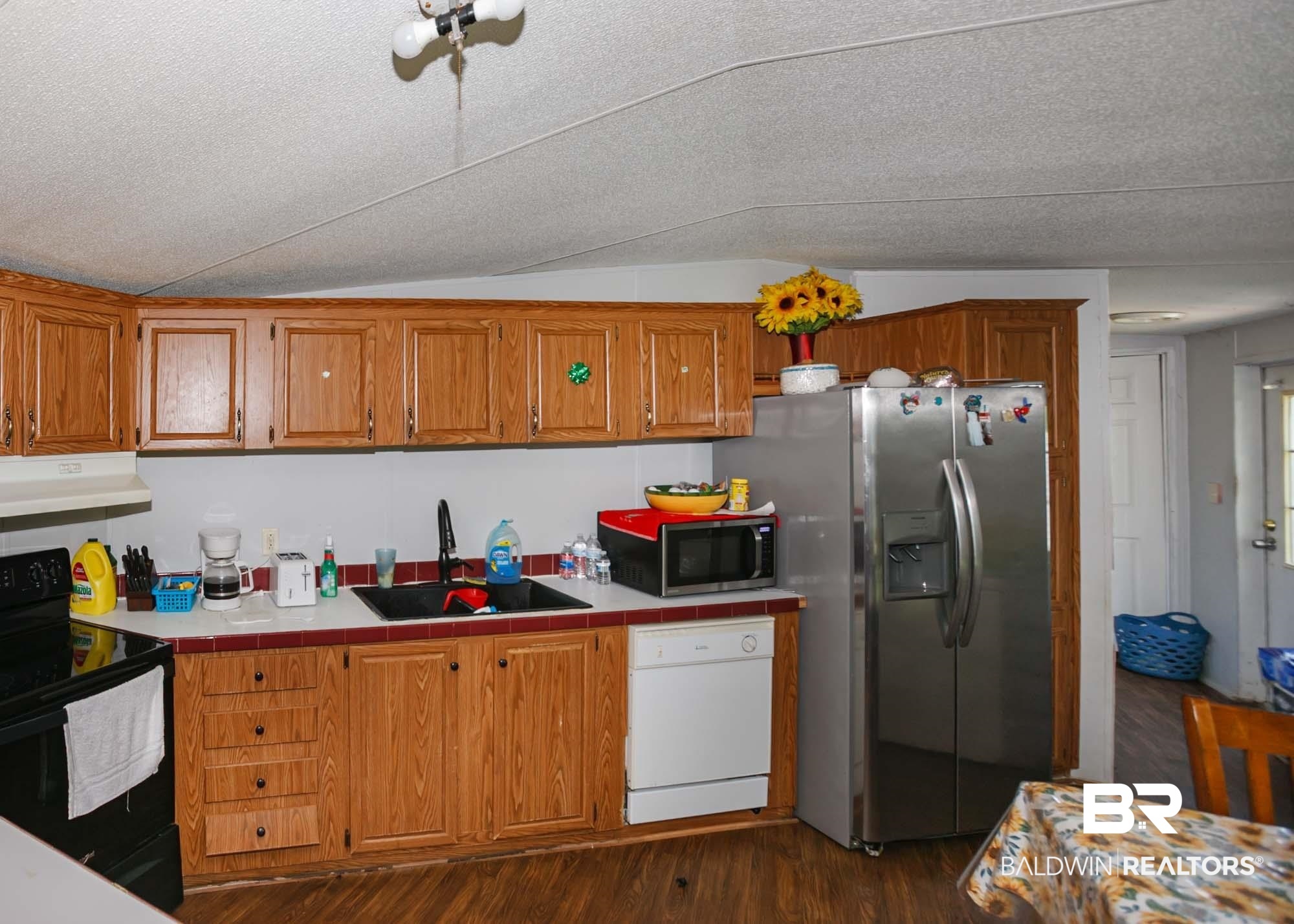 14005 County Road 49 Foley, AL 36535 - Photo 7 of 38 Kitchen with black electric range oven, brown cabinetry, white dishwasher, vaulted ceiling, and stainless steel fridge with ice dispenser