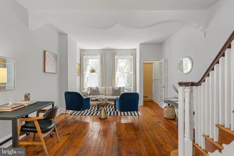 a living room with furniture and a dining table with wooden floor