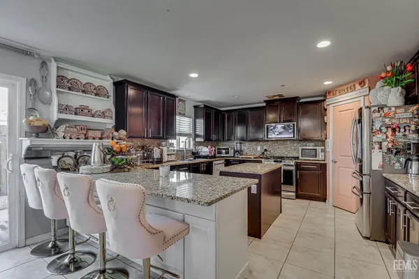 a kitchen with kitchen island a stove a sink a refrigerator and chairs