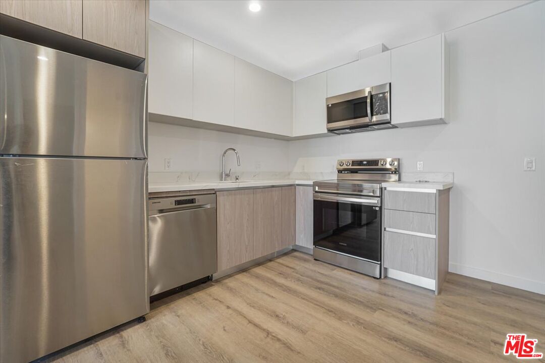 10918 Camarillo Street, Unit 103 North Hollywood, CA 91602 - Photo 12 of 38 a kitchen with stainless steel appliances a refrigerator stove and microwave