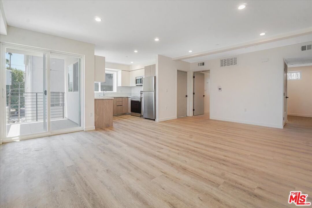 10918 Camarillo Street, Unit 103 North Hollywood, CA 91602 - Photo 29 of 38 a view of an empty room with wooden floor and a kitchen