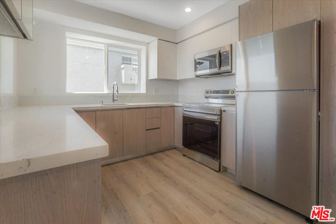 10918 Camarillo Street, Unit 103 North Hollywood, CA 91602 - Photo 33 of 38 a kitchen with stainless steel appliances granite countertop a refrigerator a sink dishwasher a stove with wooden cabinets