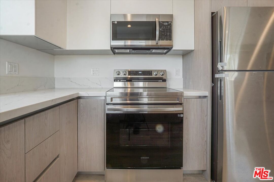 10918 Camarillo Street, Unit 103 North Hollywood, CA 91602 - Photo 35 of 38 a kitchen with stainless steel appliances granite countertop a stove and a refrigerator