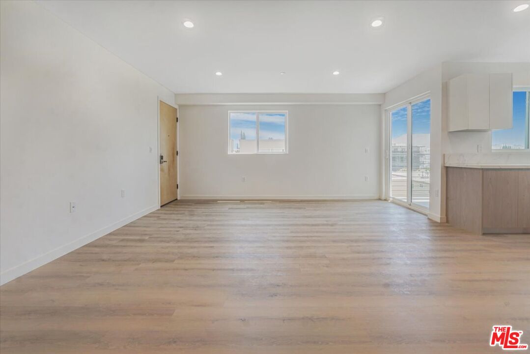 10918 Camarillo Street, Unit 103 North Hollywood, CA 91602 - Photo 38 of 38 a view of an empty room with wooden floor and a kitchen