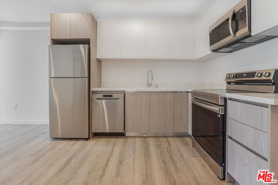 10918 Camarillo Street, Unit 103 North Hollywood, CA 91602 - Photo 10 of 38 a kitchen with a refrigerator sink and cabinets